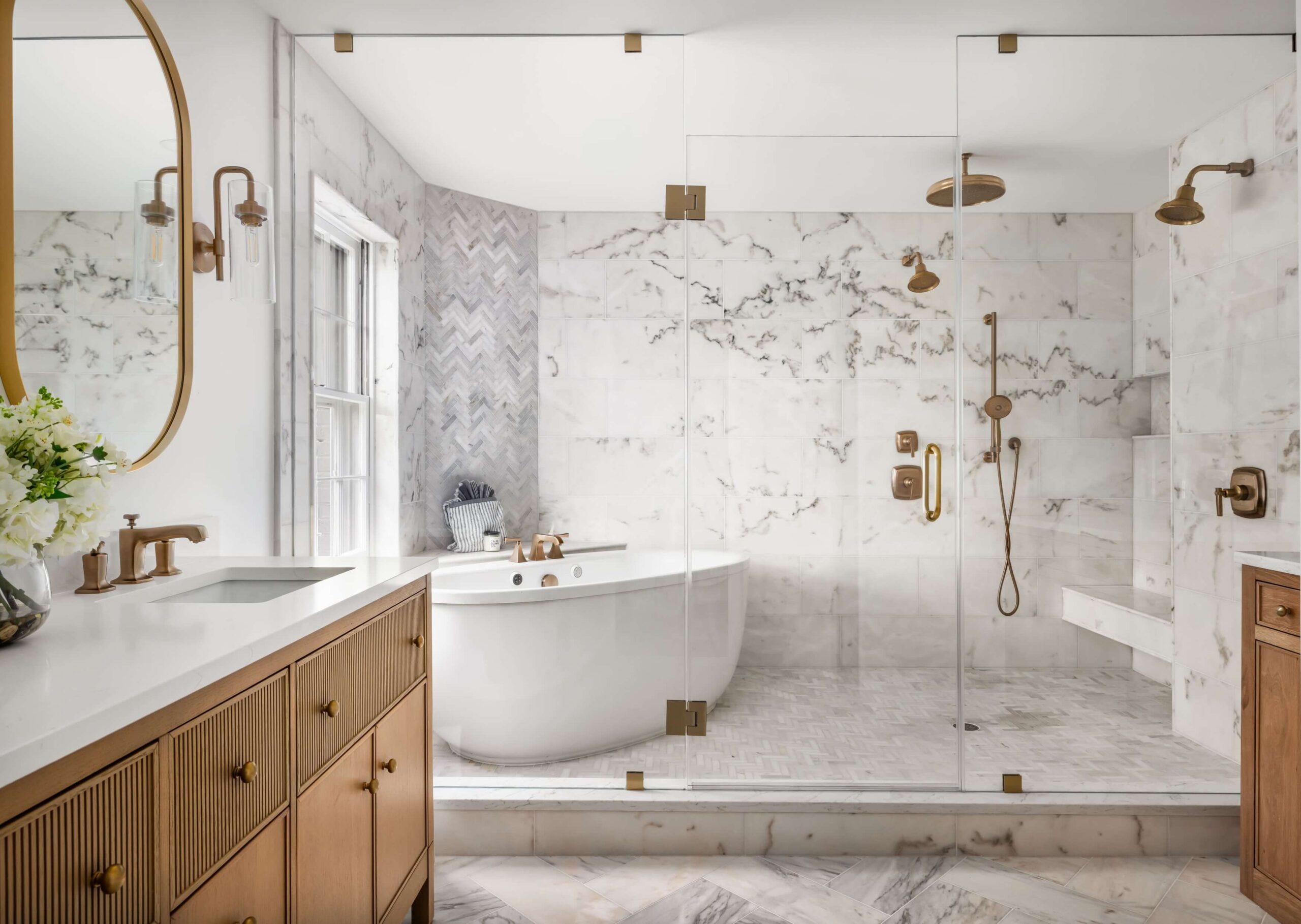 Luxury marble bathroom renovation with freestanding tub, glass-enclosed shower, and brass fixtures in Northern Virginia.
